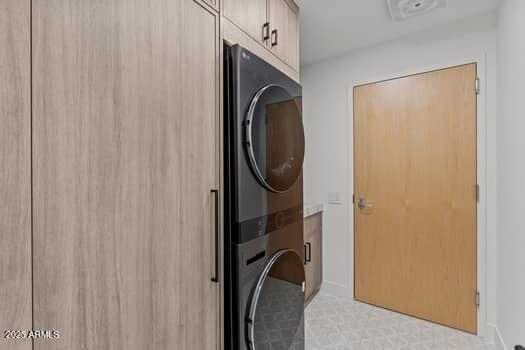 laundry area with cabinet space and stacked washer and clothes dryer