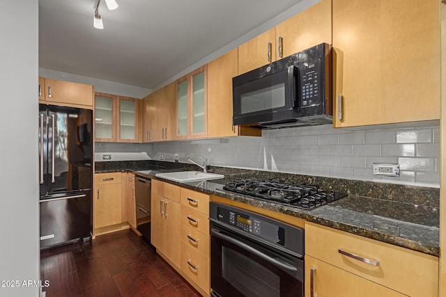 kitchen featuring tasteful backsplash, dark hardwood / wood-style floors, black appliances, sink, and dark stone counters