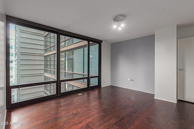 empty room featuring floor to ceiling windows, dark hardwood / wood-style flooring, and a healthy amount of sunlight