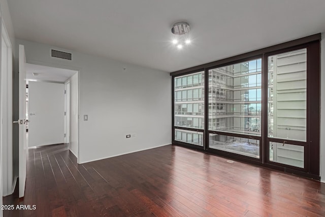 spare room featuring a wall of windows and dark wood-type flooring