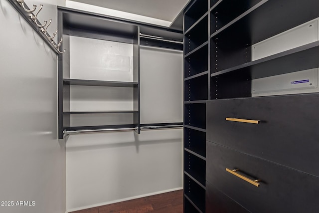 spacious closet featuring dark hardwood / wood-style flooring and a wall unit AC