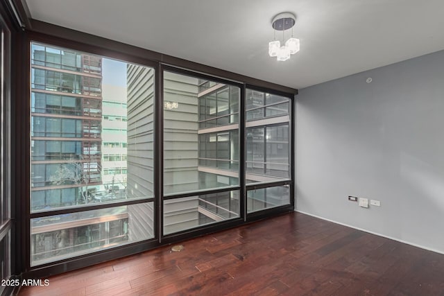 unfurnished room featuring wood-type flooring and a notable chandelier