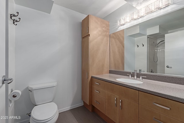 bathroom with toilet, vanity, and tiled shower