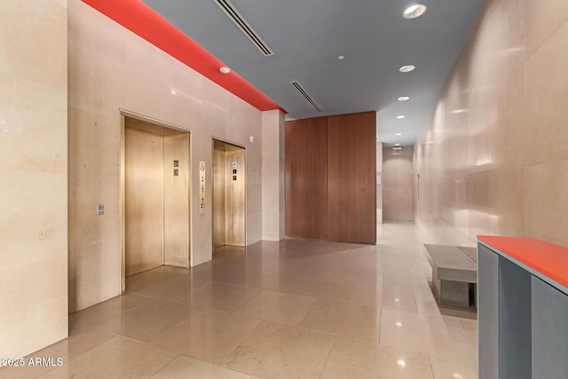 hall with tile walls, light tile patterned floors, and elevator