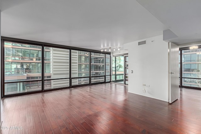 unfurnished room with floor to ceiling windows, rail lighting, and hardwood / wood-style flooring