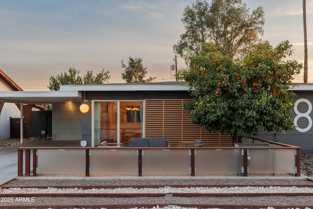 back house at dusk featuring a carport