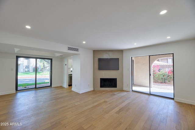 unfurnished living room featuring recessed lighting, a large fireplace, visible vents, and light wood finished floors