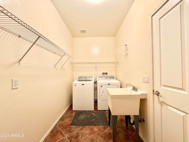 laundry room with washer and clothes dryer, dark tile patterned floors, and sink