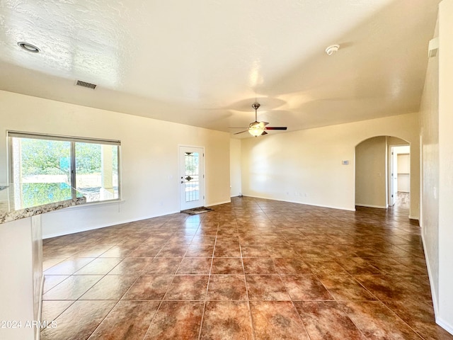 interior space featuring dark tile patterned floors, a textured ceiling, and ceiling fan