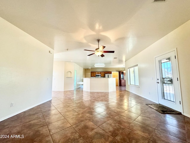 unfurnished living room featuring ceiling fan and dark tile patterned floors