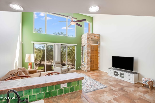 living room featuring ceiling fan, sink, and a towering ceiling