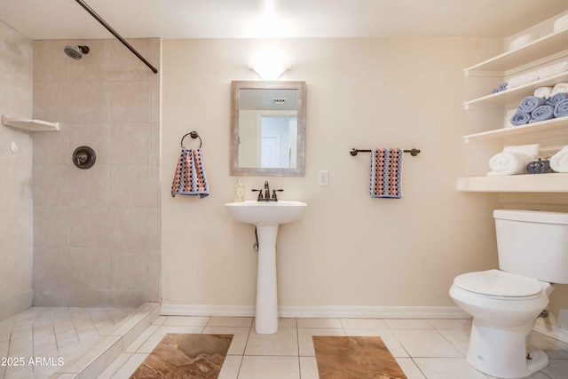 bathroom with tile patterned flooring, a tile shower, and toilet