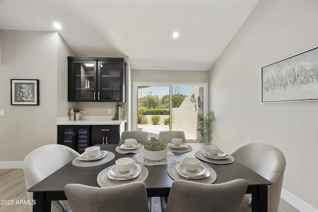 10538 E Gold Dust Cir, Scottsdale, AZ 85258 - dining space with wine cooler, a dry bar, light wood-style flooring, vaulted ceiling, and recessed lighting