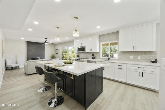 10538 E Gold Dust Cir, Scottsdale, AZ 85258 - kitchen with appliances with stainless steel finishes, white cabinets, light wood-type flooring, decorative backsplash, and recessed lighting