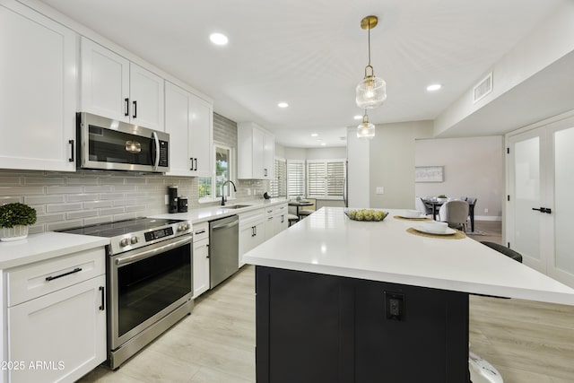 10538 E Gold Dust Cir, Scottsdale, AZ 85258 - kitchen with stainless steel appliances, tasteful backsplash, white cabinets, a center island, and light countertops
