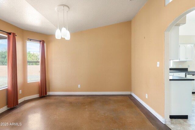 unfurnished dining area with baseboards, arched walkways, and concrete flooring