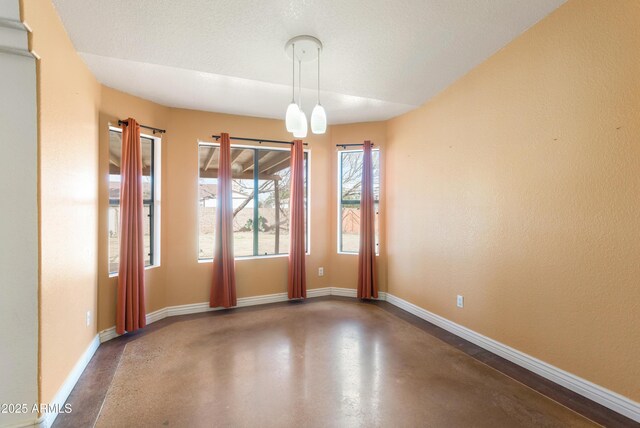 unfurnished room with concrete floors and baseboards