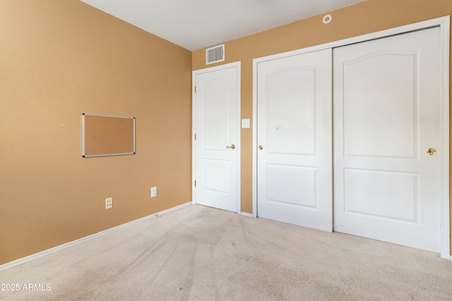 unfurnished bedroom featuring a closet, visible vents, and carpet flooring