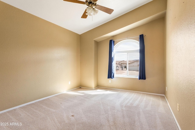 carpeted empty room with baseboards, a ceiling fan, and a textured wall