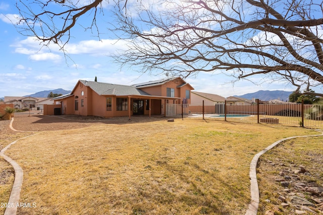 rear view of property featuring a fenced in pool, a patio, a fenced backyard, a mountain view, and stucco siding