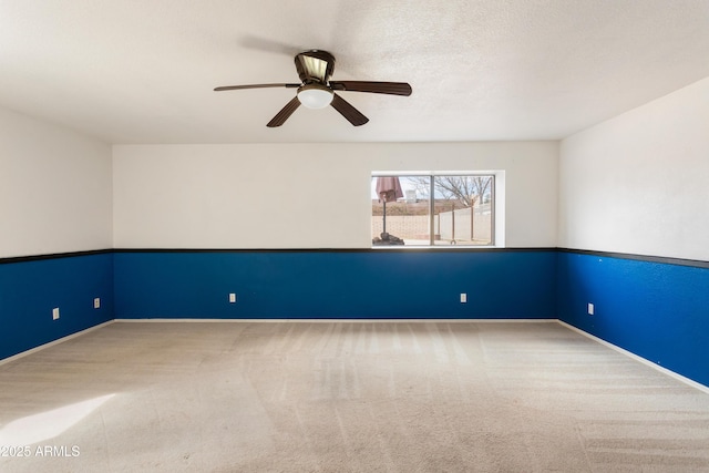 carpeted spare room with a textured ceiling, ceiling fan, and baseboards