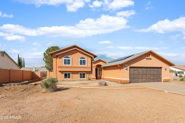 view of front of property featuring solar panels, stucco siding, concrete driveway, an attached garage, and fence