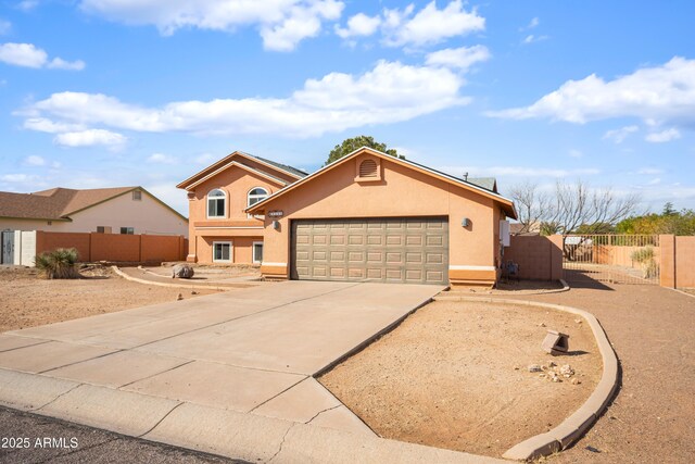 view of front of home with concrete driveway, an attached garage, a gate, fence, and stucco siding