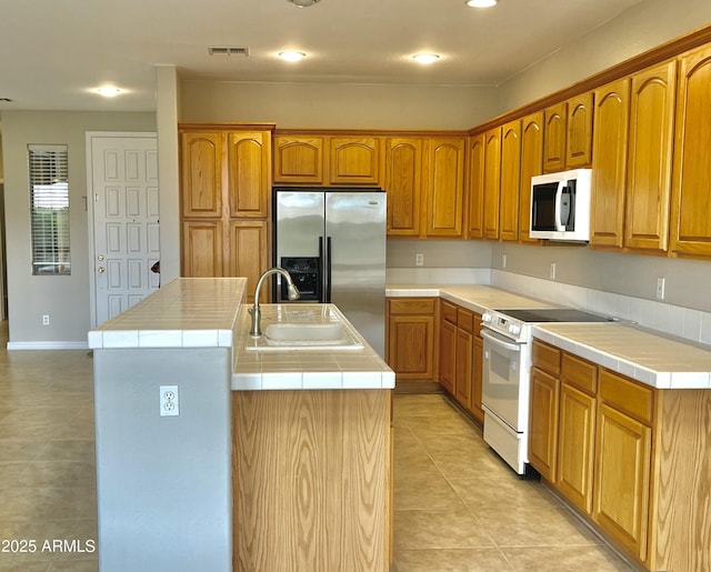 3421 W Warren Dr, Anthem, AZ 85086 - kitchen with tile counters, stainless steel fridge, a center island with sink, electric stove, and visible vents