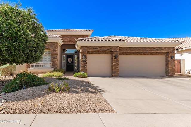 mediterranean / spanish house featuring stone siding, stucco siding, concrete driveway, an attached garage, and a tile roof