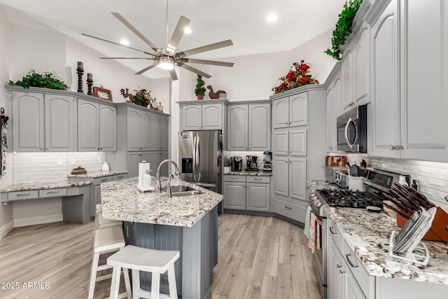 kitchen with ceiling fan, tasteful backsplash, gray cabinetry, a sink, and stainless steel appliances
