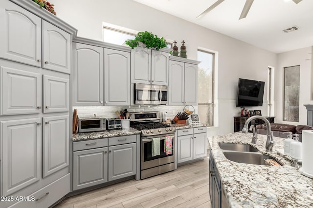 kitchen with a healthy amount of sunlight, gray cabinets, visible vents, a sink, and stainless steel appliances