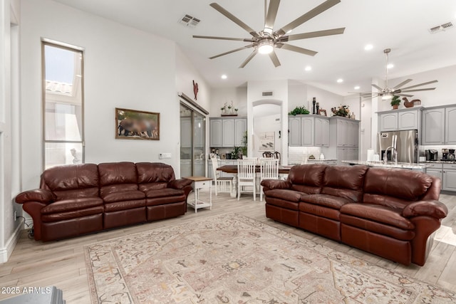 living area featuring light wood-style floors, ceiling fan, and visible vents