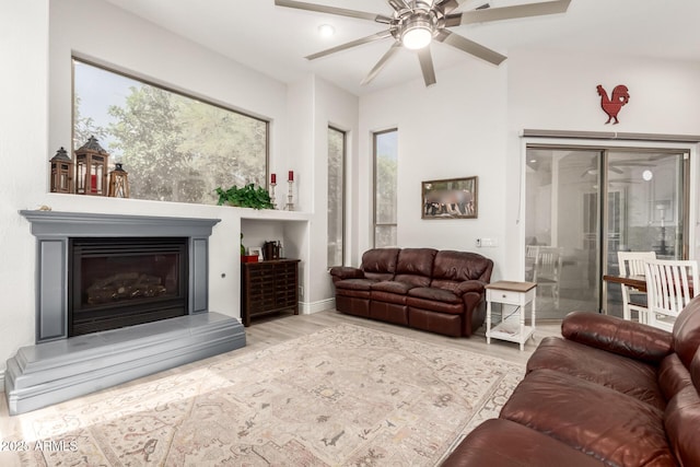 living room with ceiling fan, a glass covered fireplace, and wood finished floors