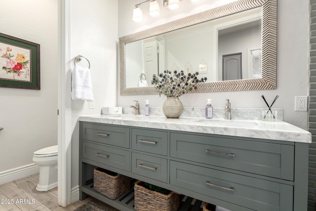 full bathroom with a sink, baseboards, toilet, and double vanity