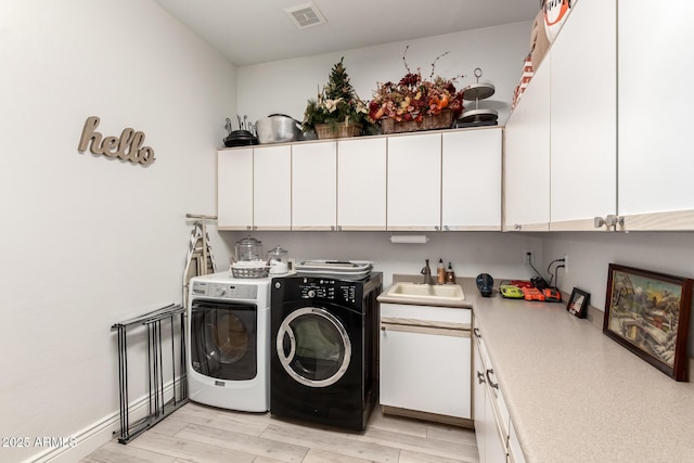 laundry room featuring independent washer and dryer, visible vents, cabinet space, a sink, and light wood-style floors