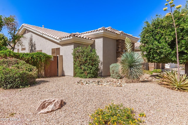 view of side of home with fence, a tile roof, and stucco siding