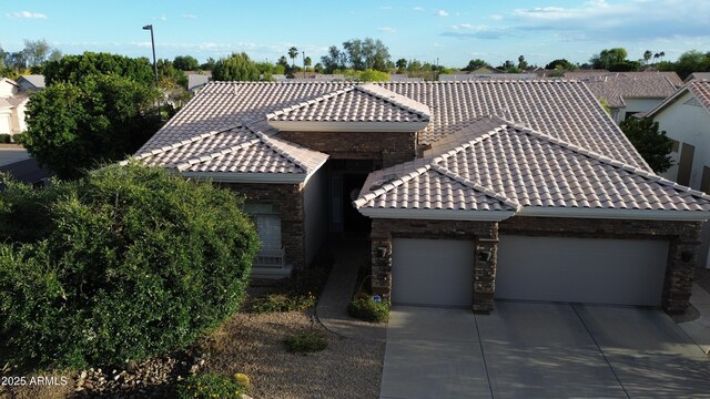 view of front of home featuring driveway, a tile roof, stone siding, and a garage