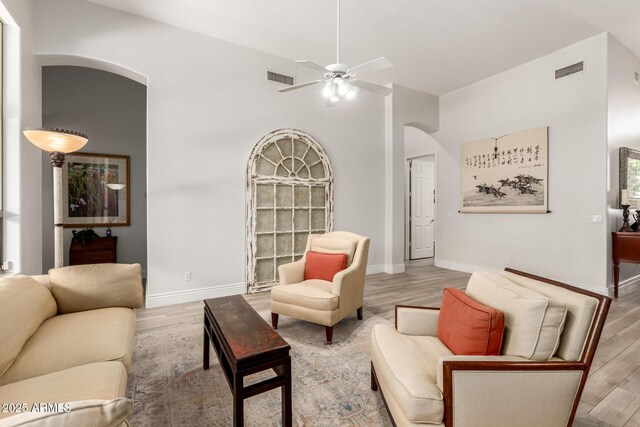 living area with arched walkways, visible vents, and wood finished floors