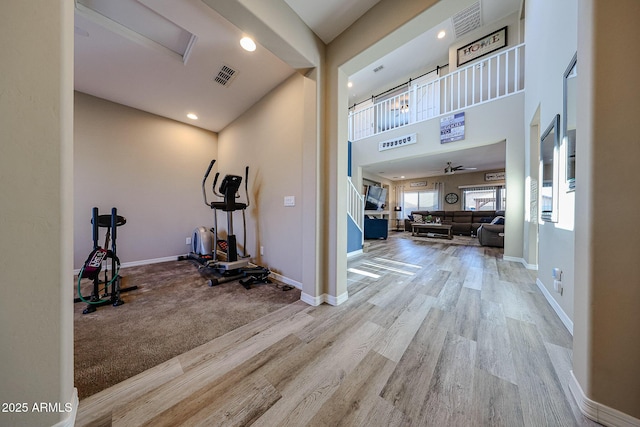 workout area with a ceiling fan, wood finished floors, visible vents, and baseboards