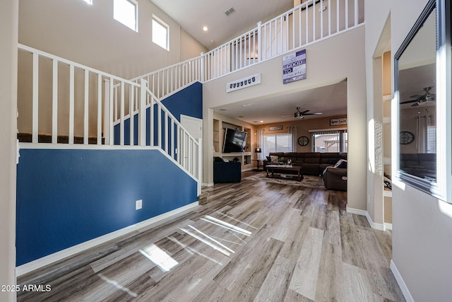 living area with visible vents, baseboards, ceiling fan, stairs, and wood finished floors
