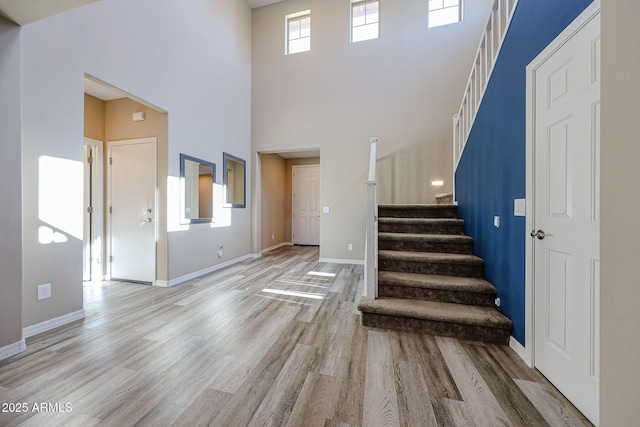 entryway with baseboards, a high ceiling, wood finished floors, and stairs