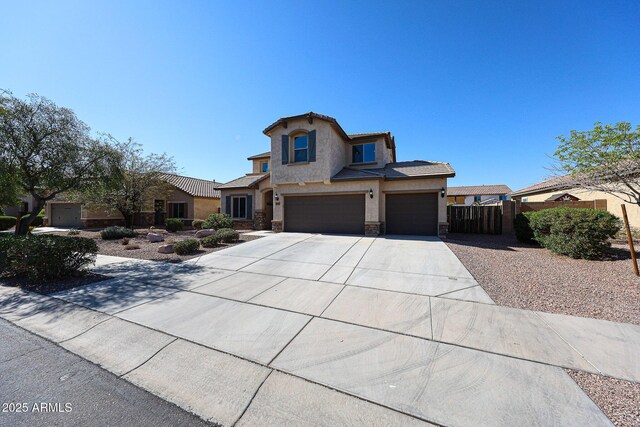 view of front of property with an attached garage, fence, stucco siding, stone siding, and driveway