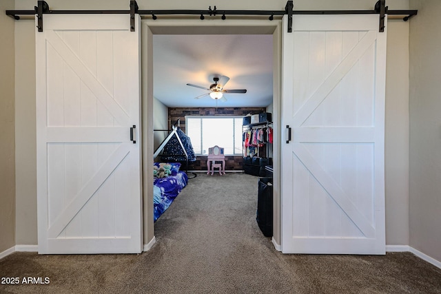 bedroom with a barn door, baseboards, and dark colored carpet