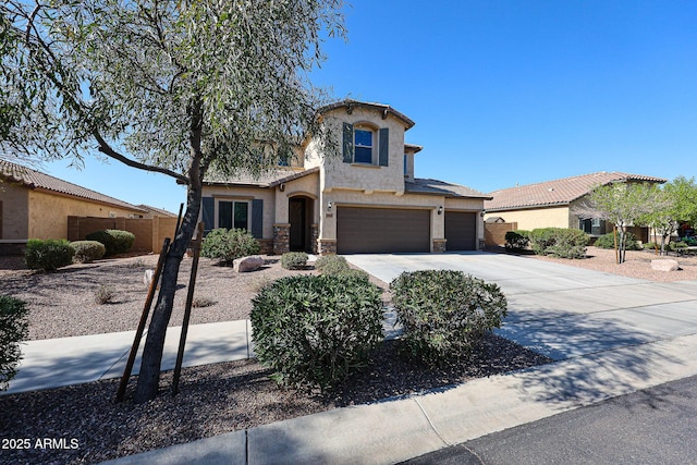 mediterranean / spanish-style home with fence, concrete driveway, stucco siding, stone siding, and an attached garage