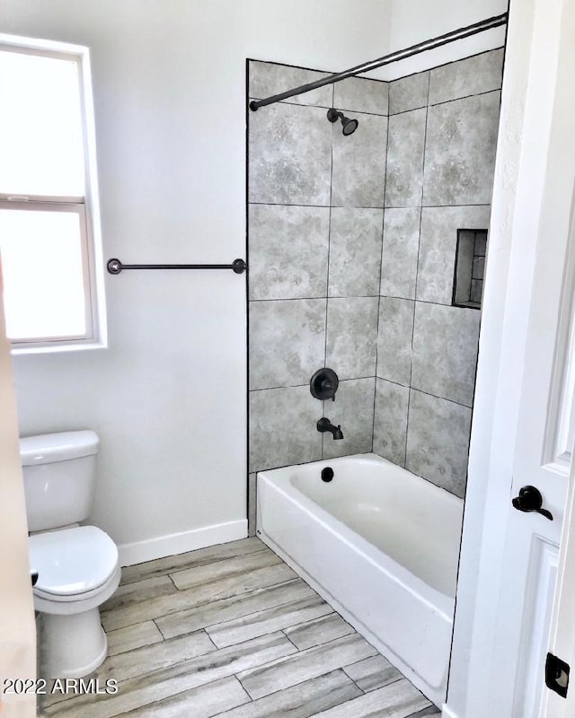 bathroom featuring tiled shower / bath combo and toilet