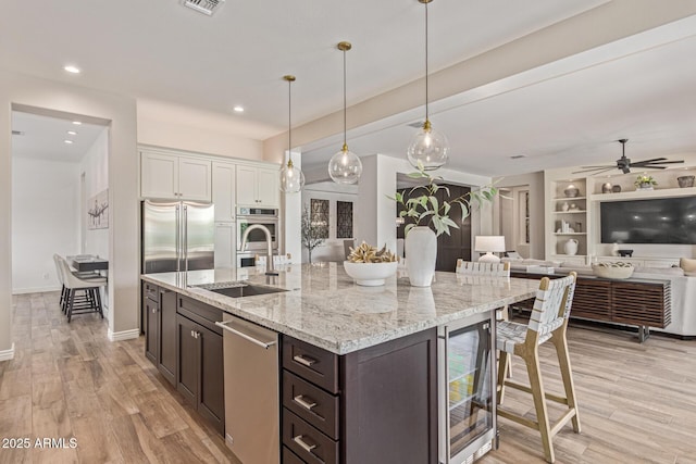 3400 S Whetstone Pl, Chandler, AZ 85286 - kitchen with beverage cooler, a sink, stainless steel appliances, a breakfast bar area, and dark brown cabinets