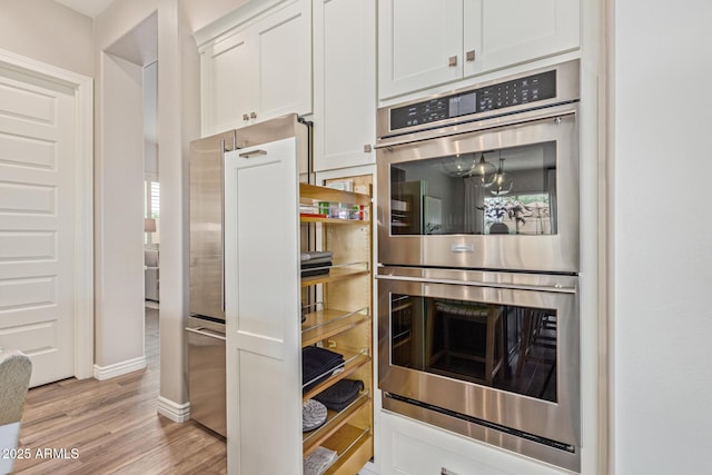3400 S Whetstone Pl, Chandler, AZ 85286 - kitchen with double oven, light wood finished floors, white cabinetry, high quality fridge, and baseboards