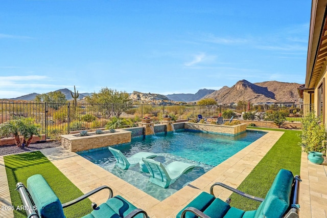 view of swimming pool with pool water feature, a mountain view, and a lawn