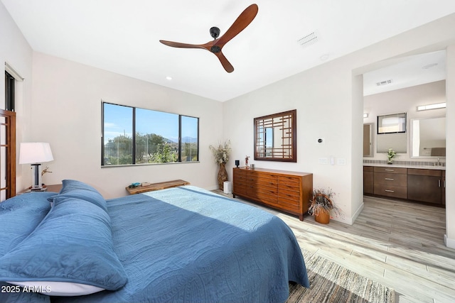 bedroom featuring ceiling fan, light wood-type flooring, and ensuite bath