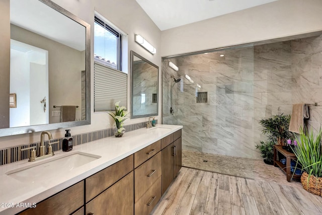 bathroom with a tile shower, vanity, and wood-type flooring